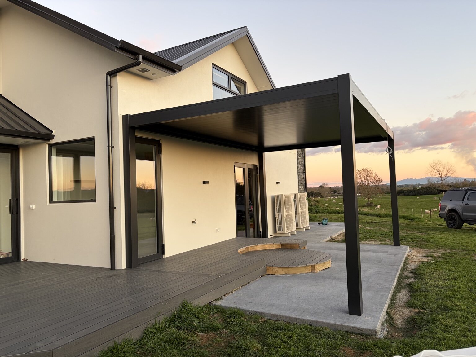 Completed dark aluminium louvre roof integrated with a rural home and deck