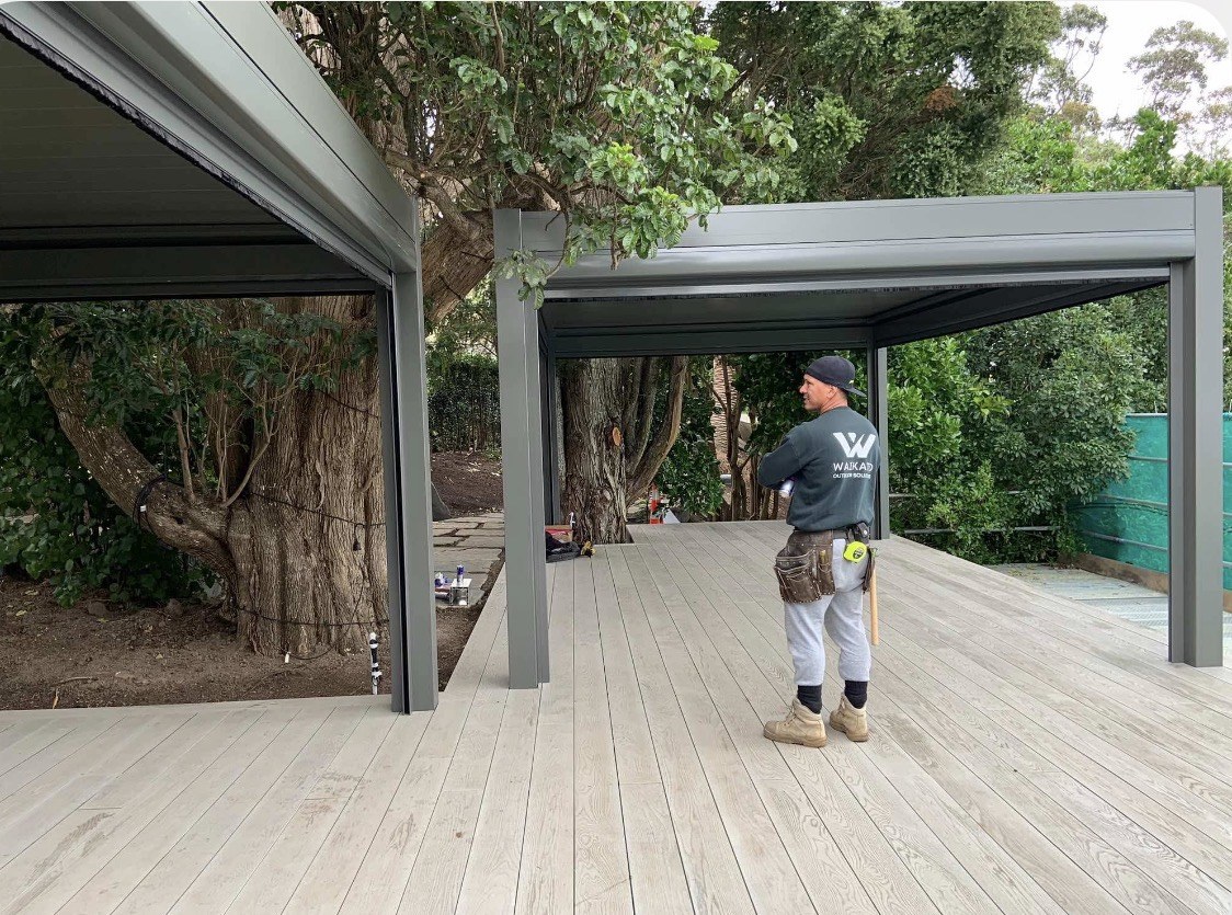 Two louvred pergolas positioned beside a mature tree on the Mission Bay entertainment deck