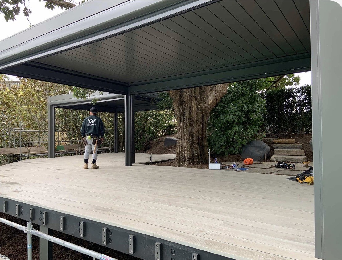 Twin louvred pergolas and composite decking fitted around established trees in Mission Bay, Auckland