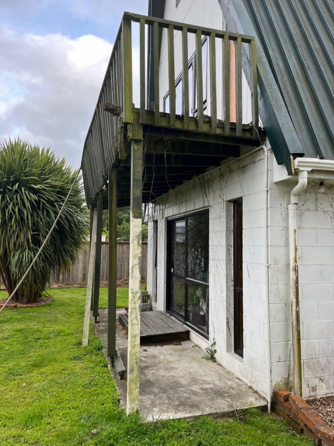 Before GRIT's deck build: bare concrete beneath a weathered elevated timber deck in Pirongia