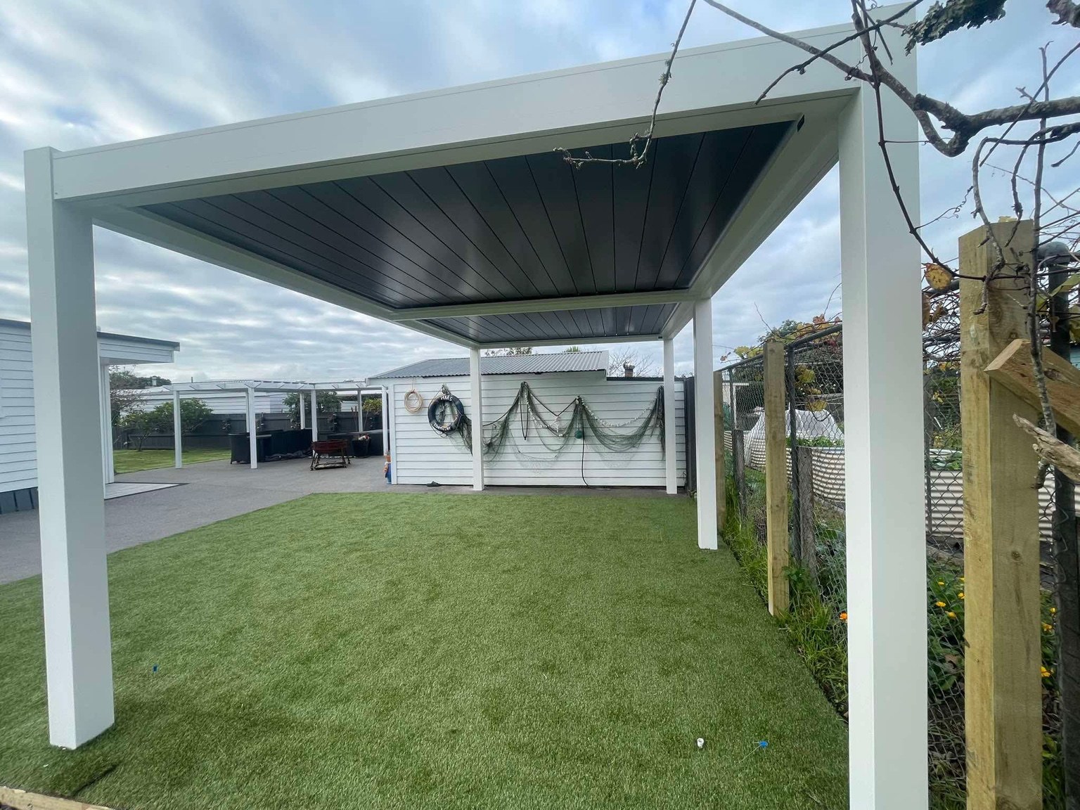 Two-tone louvred pergola installed by GRIT in Raglan, Waikato, with a white frame and deep blue roof louvres
